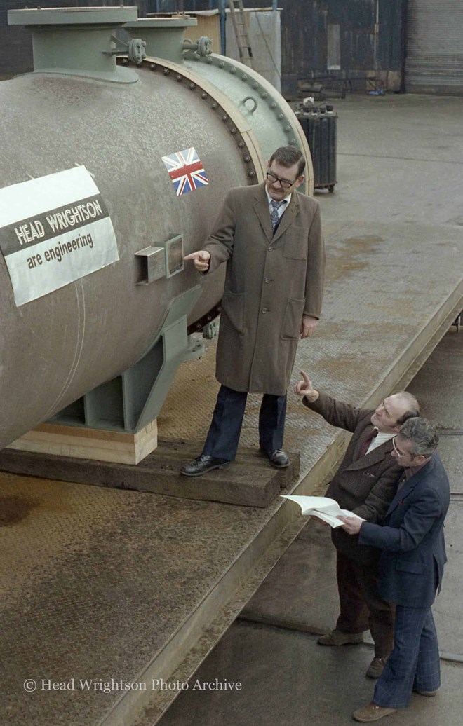 3 men looking at large pipe