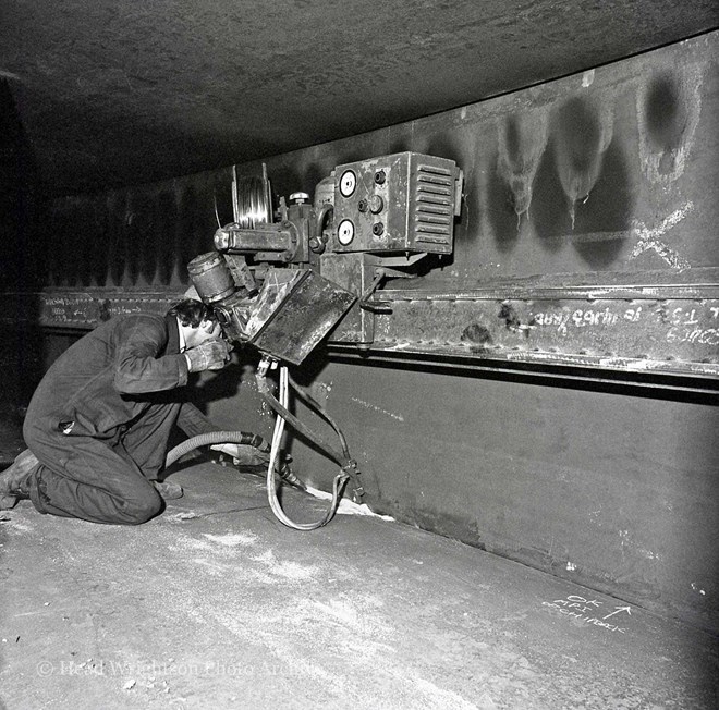 Men welding various structures in workshop