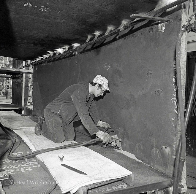 Men welding various structures in workshop