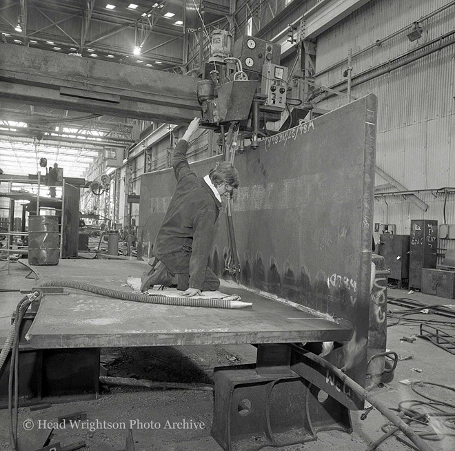 Men welding various structures in workshop