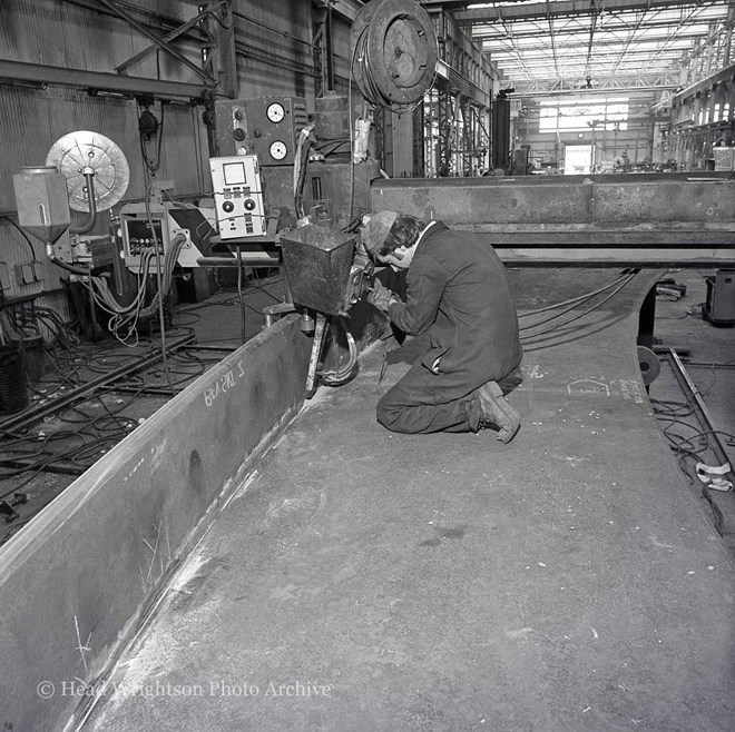 Men welding various structures in workshop